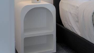 A bed with white bedding and a nightstand with a lamp.