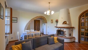 A living room with a grey sofa, a fireplace, and a dining area with a table and chairs. - Awesome home in Monte San Savino with WiFi (Monte San Savino)