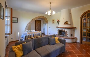 Ein Wohnzimmer mit grauem Sofa, Kamin und Essbereich mit Tisch und Stühlen.