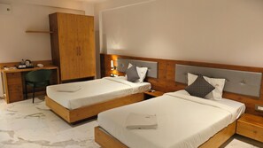Una habitación de hotel con dos camas, un armario de madera, un escritorio y una silla.