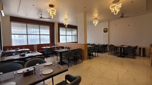 Un restaurante con varias mesas, sillas e iluminación moderna.