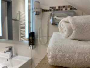 Un baño con lavamanos blanco, una toalla y un espejo.