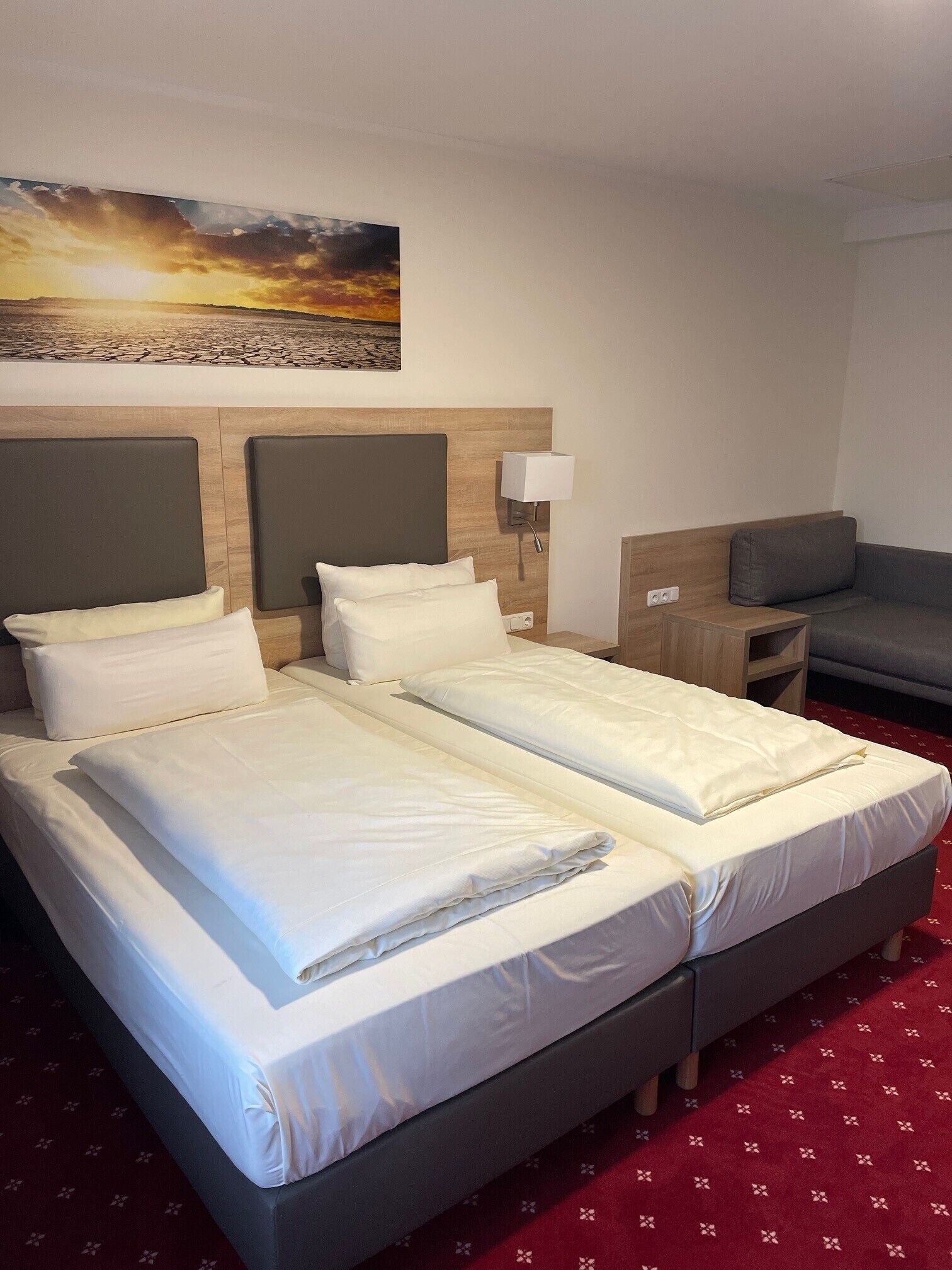 Ein Hotelzimmer mit einem großen Bett, einem Nachttisch, einer Lampe, einem Sofa und einem Gemälde an der Wand.