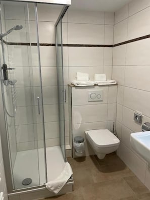 Un baño pequeño con cabina de ducha de vidrio, inodoro y lavamanos.