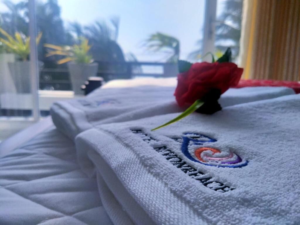 A neatly folded white towel with a logo on it, placed on a bed.