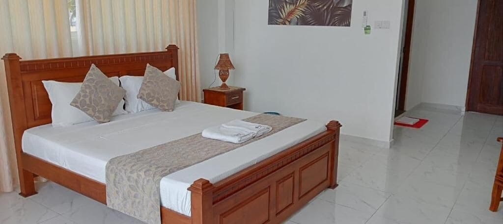A neatly made bed with a wooden frame, a bedside table with a lamp, and a wall-mounted artwork.