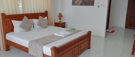 Una cama bien hecha con estructura de madera, una mesita de noche con lámpara y una obra de arte en la pared.