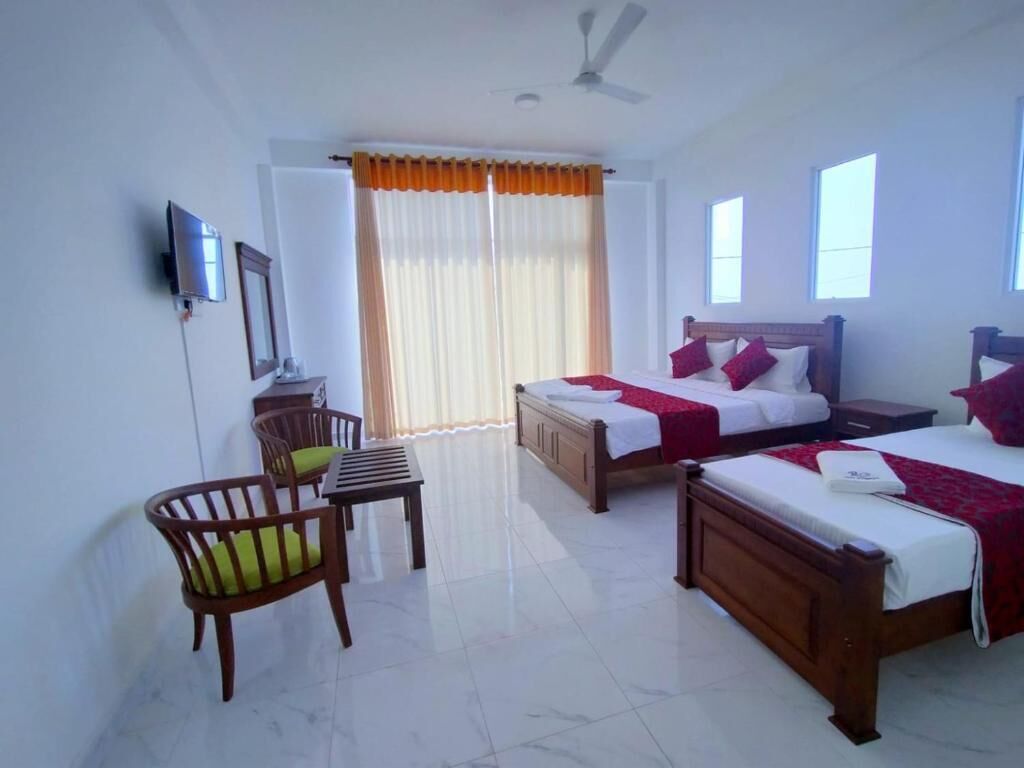 Une chambre d’hôtel avec deux lits, un bureau, une chaise et un téléviseur.