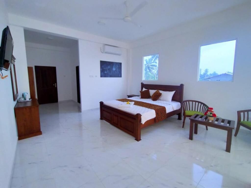 A bedroom with a bed, a chair, a small table, and a window.
