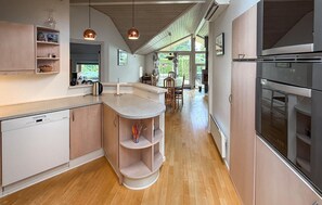 A modern kitchen with a wooden floor, built-in appliances, and pendant lighting. - Gorgeous home in Nysted with WiFi (Nysted)