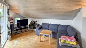 A modern living room with a grey sofa, a wooden coffee table, and a television on a stand. - Gorgeous home in Nysted with WiFi (Nysted)