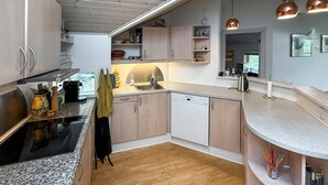 A modern kitchen with a dishwasher, granite countertops, wooden cabinets, and a view into the dining area. - Gorgeous home in Nysted with WiFi (Nysted)