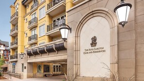 Un edificio de varios pisos con balcones, una entrada destacada con el emblema de un león y un letrero que dice "The Ritz Carlton Club and Residences".