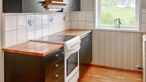 A kitchen with a stove, oven, and cabinets, a window with a view of greenery, and a tiled backsplash. - 3 bedroom lovely home in Fister (Fister)