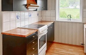 A kitchen with a stove, oven, and cabinets, a window with a view of greenery, and a tiled backsplash. - 3 bedroom lovely home in Fister (Fister)