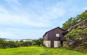 Una casa de madera rústica con escalones de piedra, rodeada de abundante vegetación y vistas al agua.