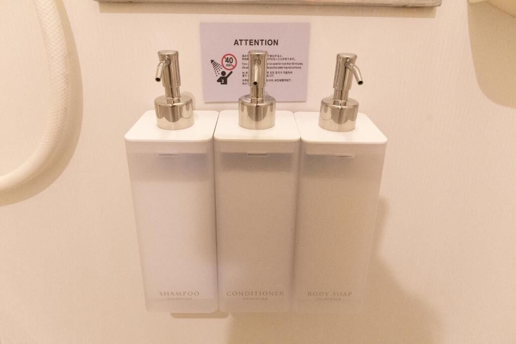 Kylpyhuoneessa on kolme annostelijaa, joissa on merkinnät: shampoo, hoitoaine ja vartalosaippua.