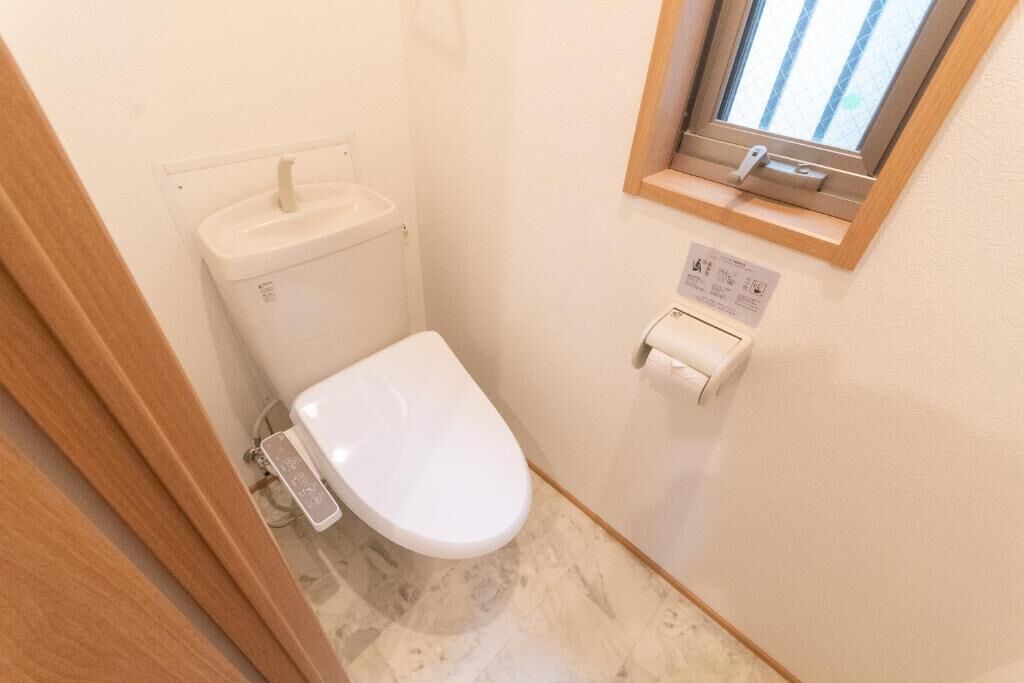 A small bathroom with a toilet, a sink, and a window.