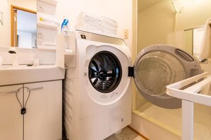 Un lavadero moderno con lavadora de carga frontal, un escurreplatos apilable y una pequeña zona de fregadero.
