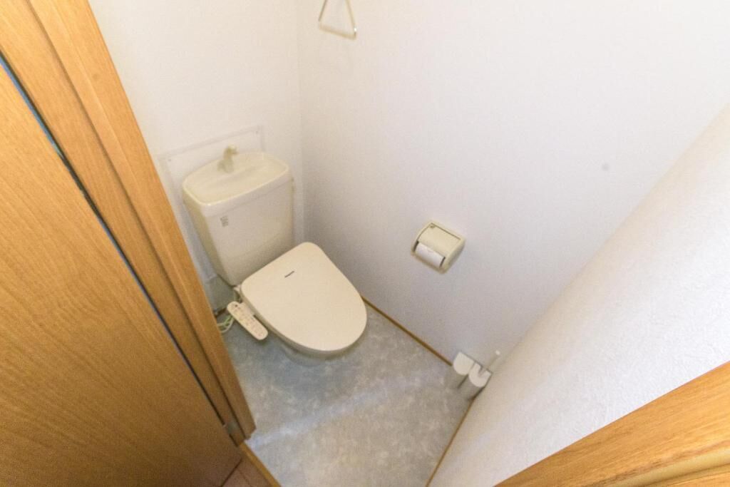 A small, narrow bathroom with a toilet, a sink, and a toilet paper holder.