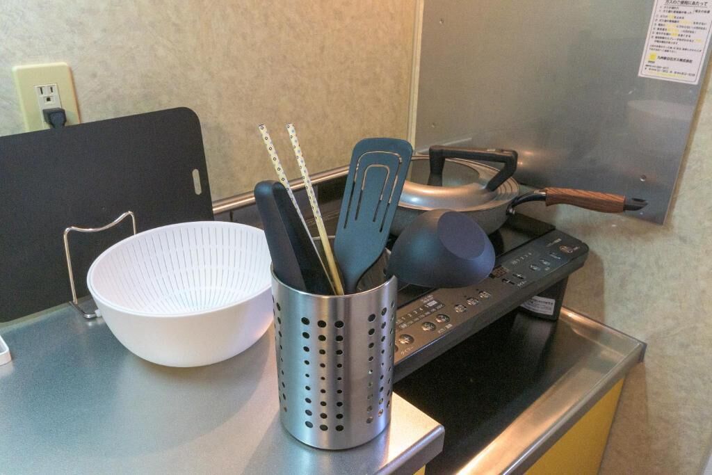 Una encimera de cocina con un bol blanco, un recipiente metálico para utensilios y una estufa.