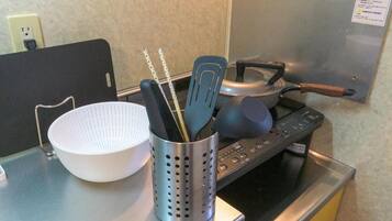 Una encimera de cocina con un bol blanco, un recipiente metálico para utensilios y una estufa.