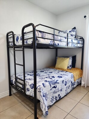Uma cama de solteiro com um edredom estampado, um cobertor amarelo e um travesseiro.