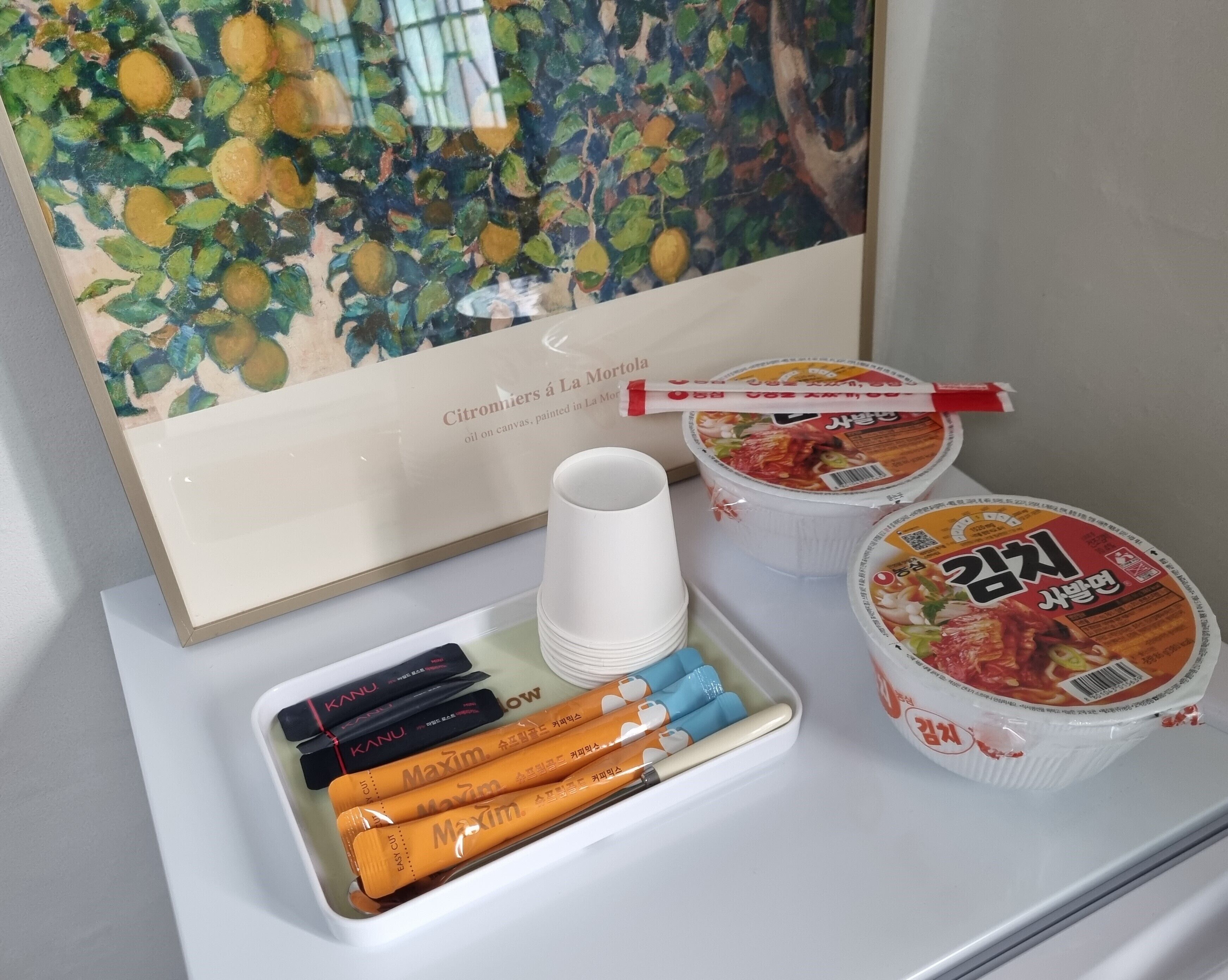 A tray with disposable cups, cutlery, and packaged food items, likely for a hotel room setting.