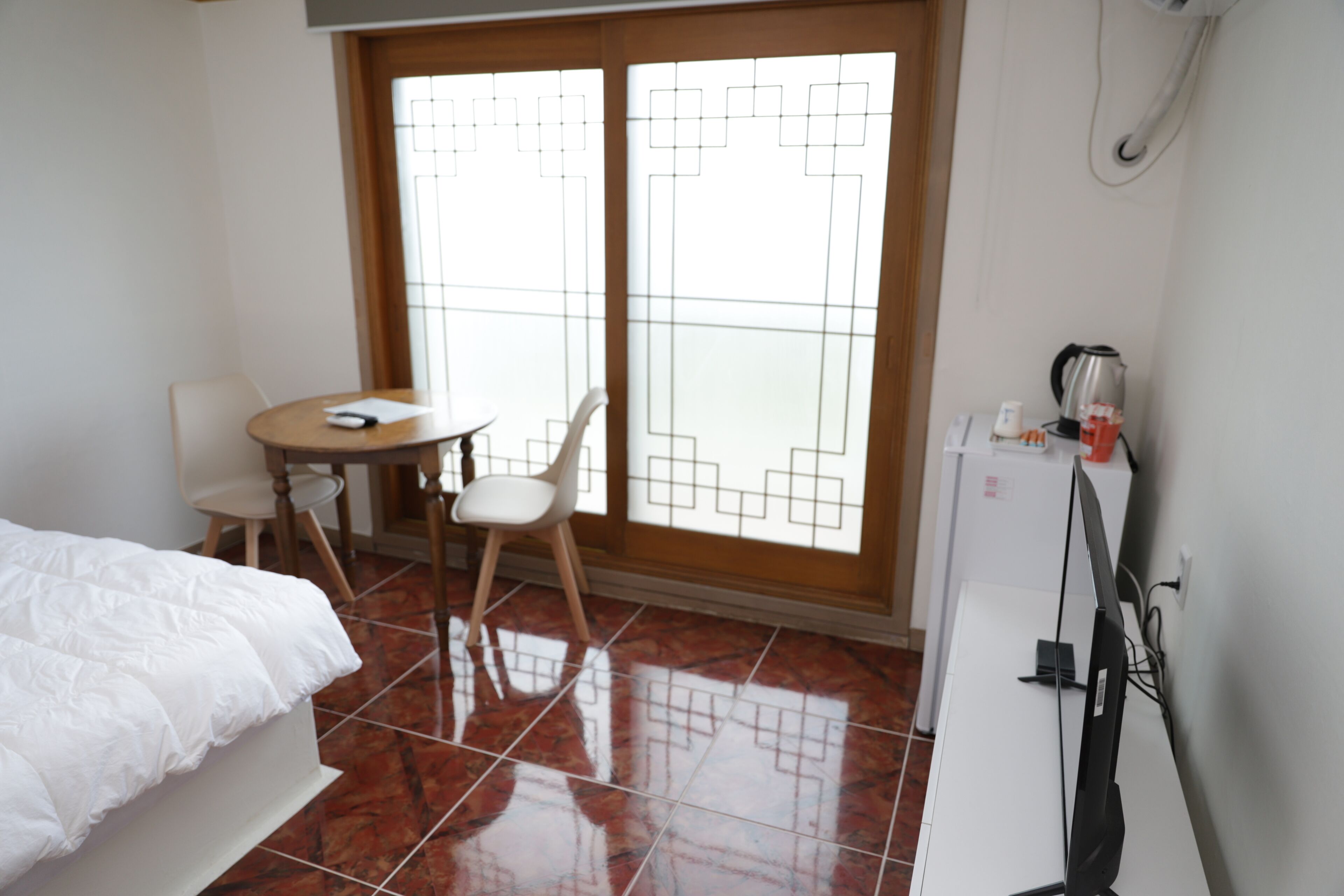 A hotel room with a bed, a desk with a chair, a coffee maker, and a TV.