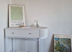 A white, ribbed cabinet with a framed artwork above it and a smaller framed artwork to the right.