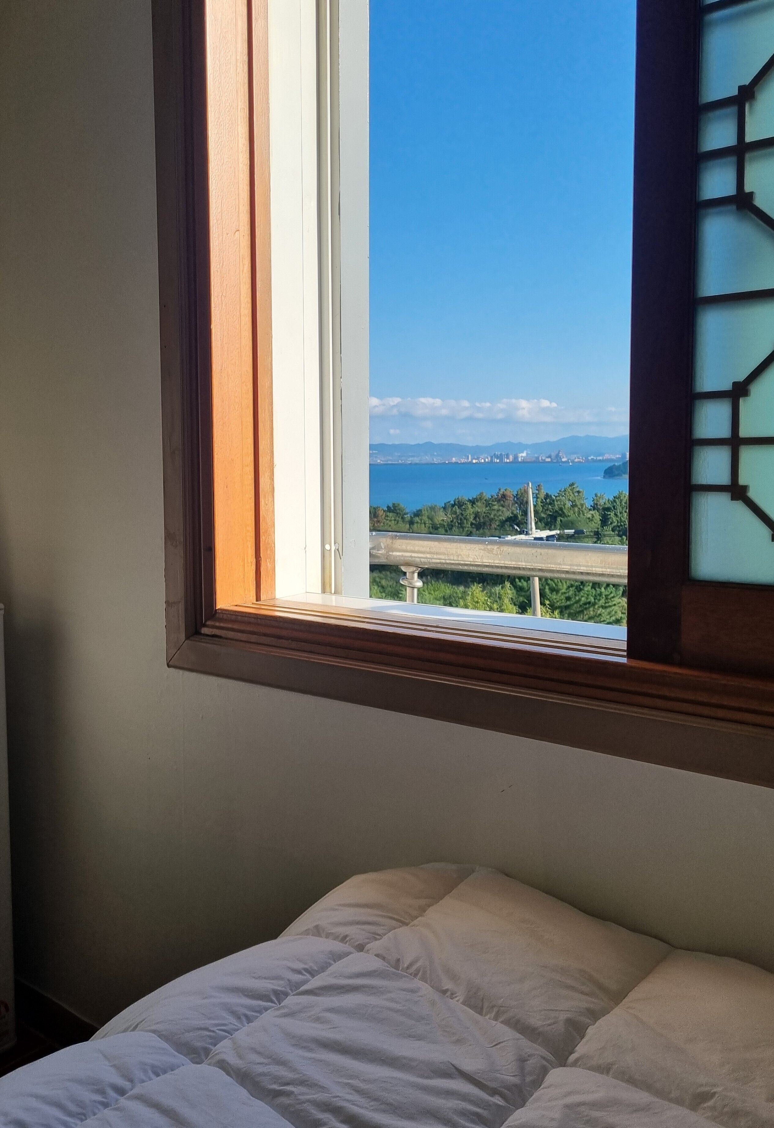 Una habitación con cama y ventana con vistas al paisaje costero.