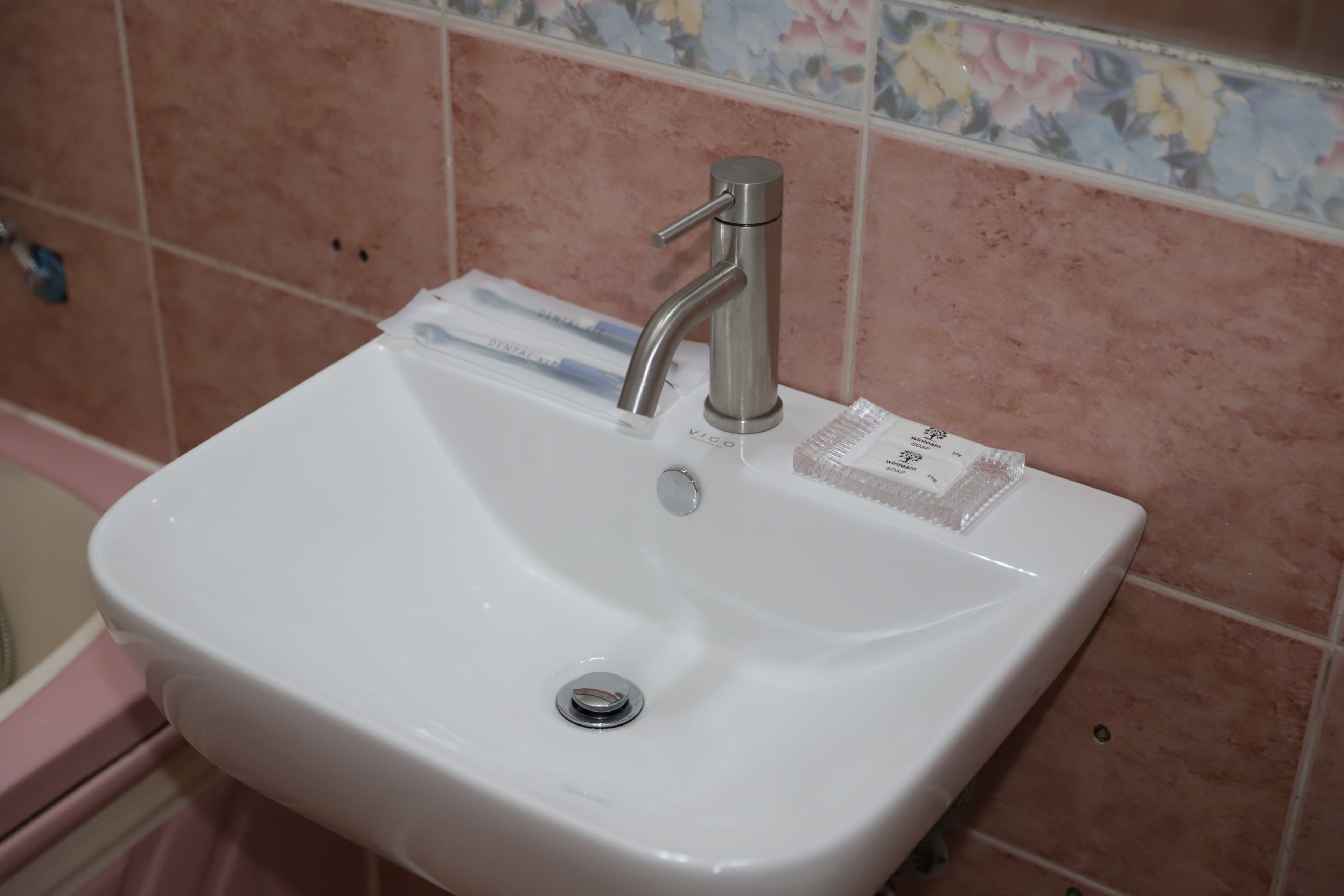 A white bathroom sink with a single faucet and a drain.