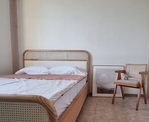 A bedroom with a bed, a chair, and a framed picture on the wall.
