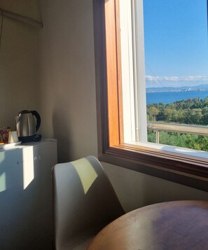 A room with a view of a coastal city, a table, a chair, and a kettle on a table. - Gloriastay (Pohang)