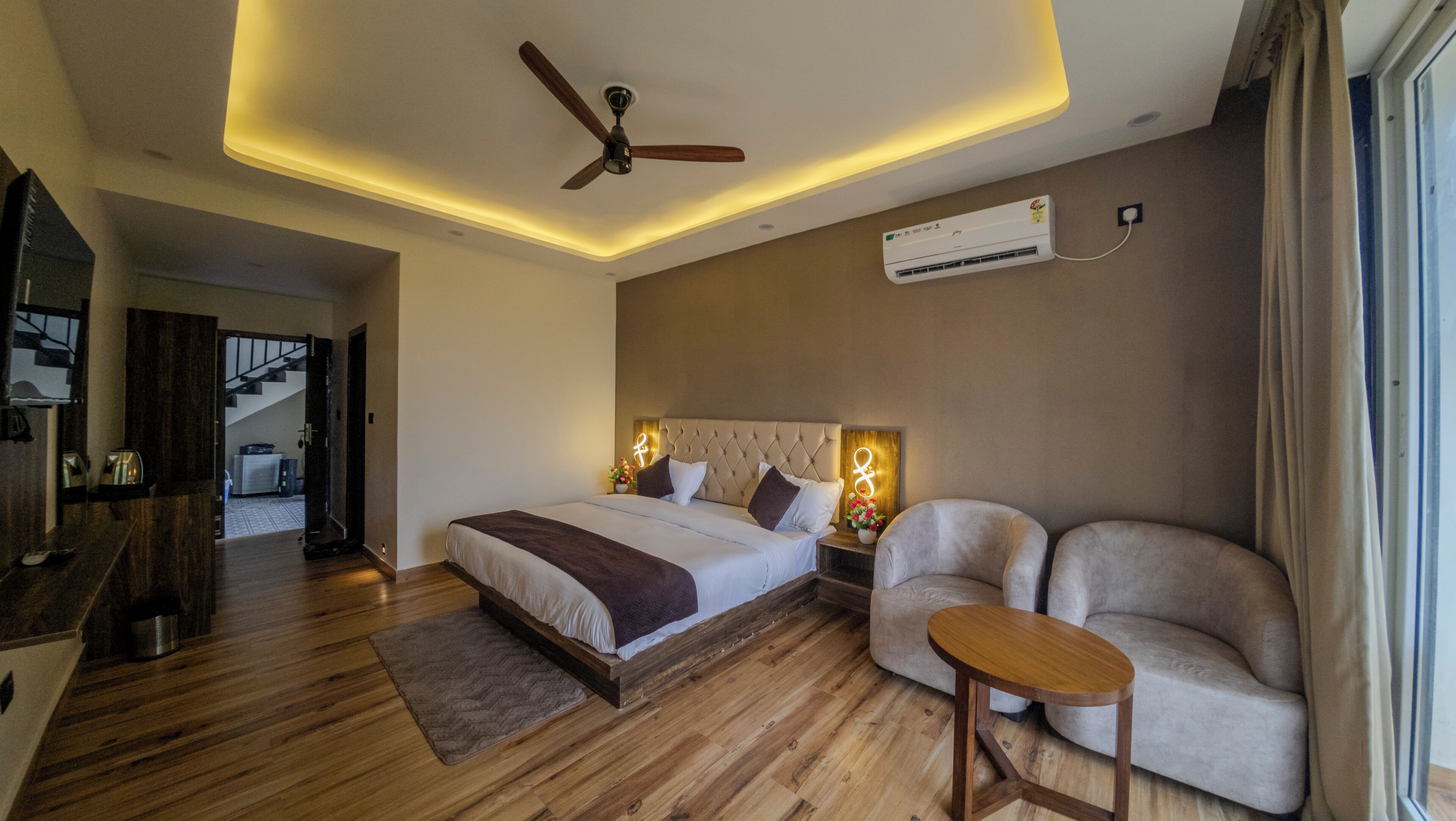 Un dormitorio con cama, ventilador de techo, aire acondicionado, sofá y una pequeña mesa.