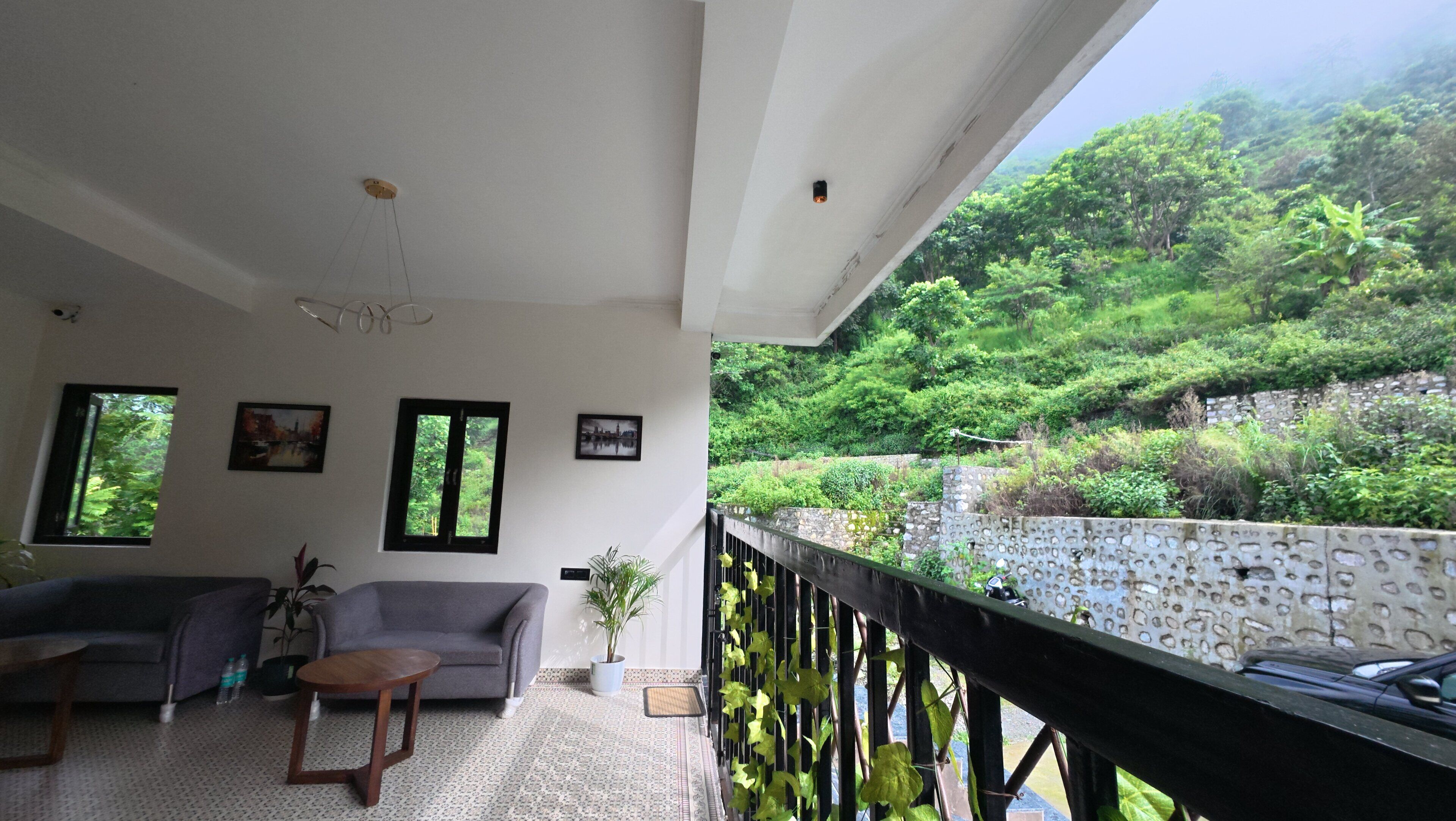 Una habitación con sofá, una mesita y vistas a un paisaje verde exuberante a través de una ventana.