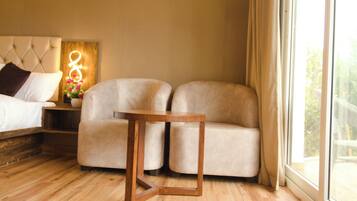 Un dormitorio moderno con cama, sofá, mesita de madera y mesita de noche con una lámpara decorativa.