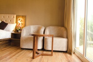 Een moderne slaapkamer met een bed, een bank, een houten bijzettafeltje en een nachtkastje met decoratieve verlichting.