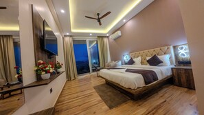 Una habitación de hotel moderna con una cama grande, un ventilador de techo, un televisor de pantalla plana y un balcón con vistas.