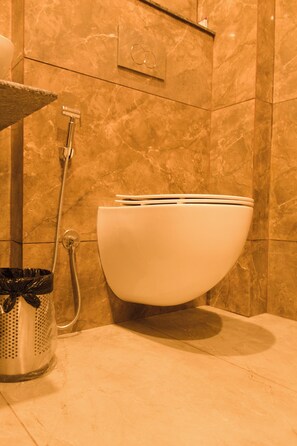 Een badkamer met een toilet, een douche en een prullenbak.