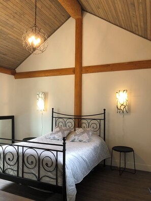 Een slaapkamer met een metalen bedframe, een houten plafond en twee wandlampen.