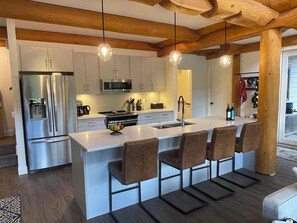 A modern kitchen with a central island, stainless steel appliances, and bar stools.