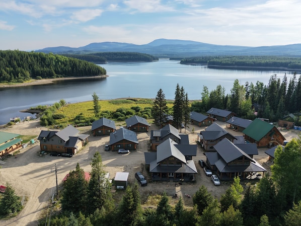 A lodge with multiple cabins, a parking area, and a lake view.