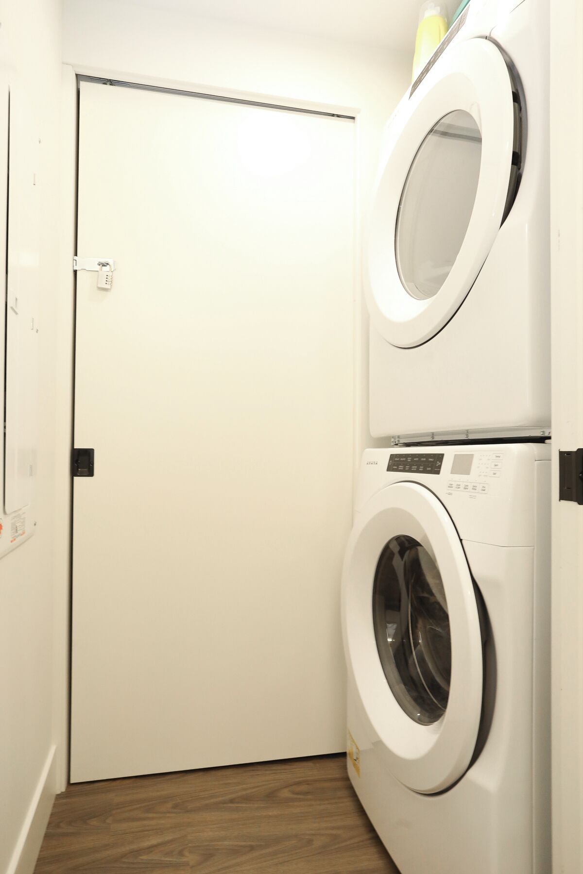 A laundry room with two stacked front-loading washing machines and a door with a light switch.