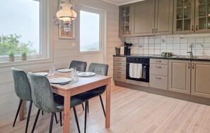 Un comedor con una mesa y sillas de madera, una araña y una cocina con armarios y estufa.