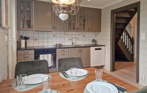 Una cocina con una mesa de comedor para dos personas, horno empotrado y una escalera que sube a otro nivel.