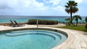 Una piscina a bordo curvo, con lettini e vista sull'oceano.