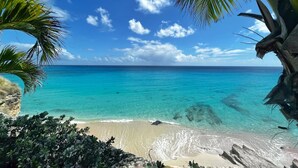 Una spiaggia con acque turchesi cristalline, palme e cielo sereno.