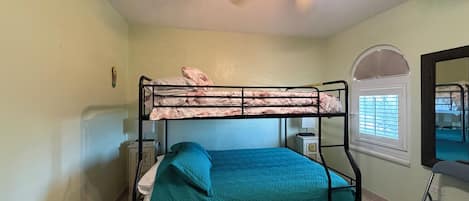 A bunk bed with a ceiling fan, a window with blinds, and a mirror on the wall.