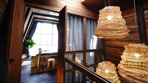 Interior de madera con un ventanal grande, una escalera y una lámpara de mimbre colgante.